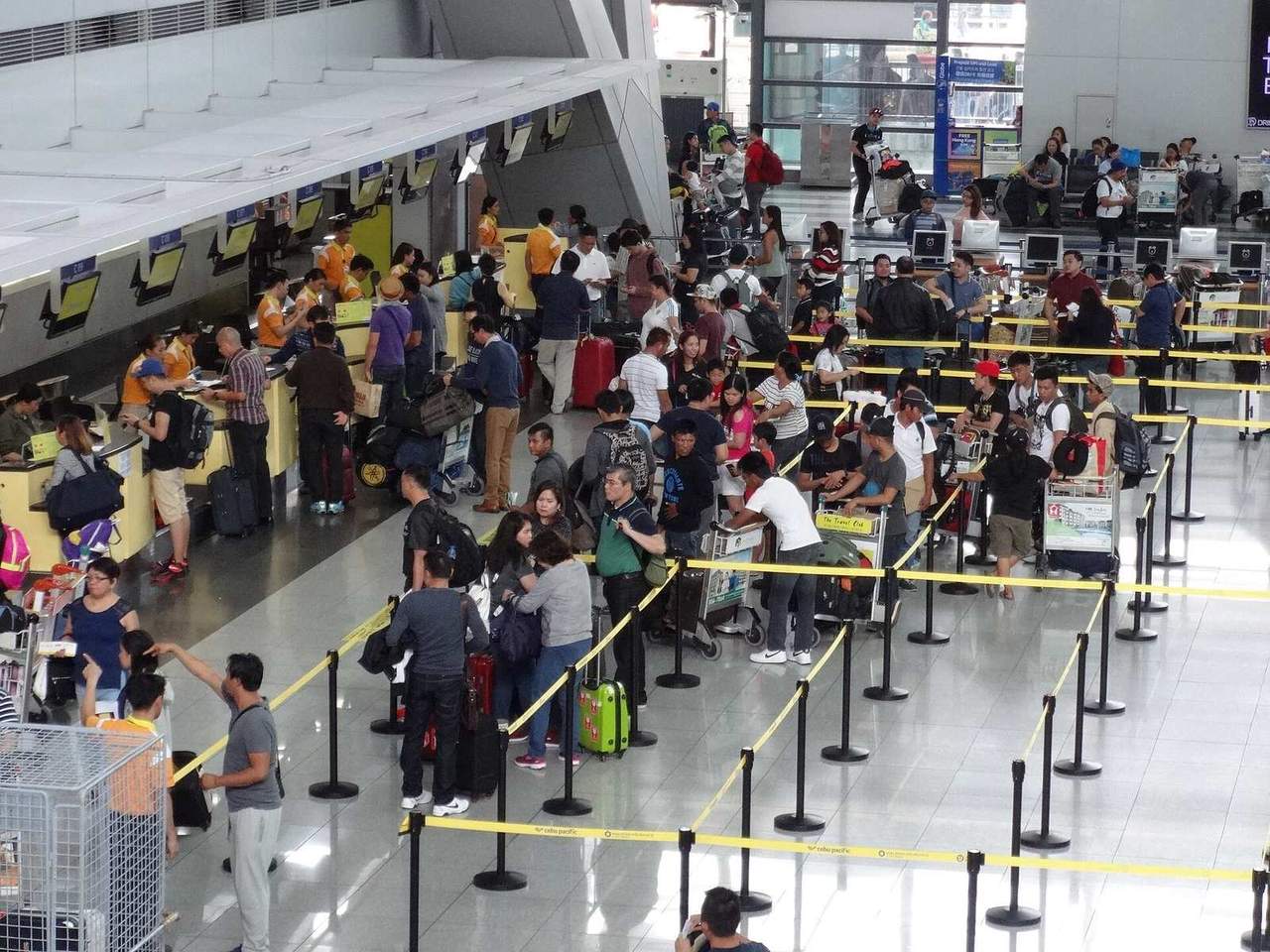 Travelers with luggage lining up at the check-in counters of NAIA Terminal 3 in Pasay